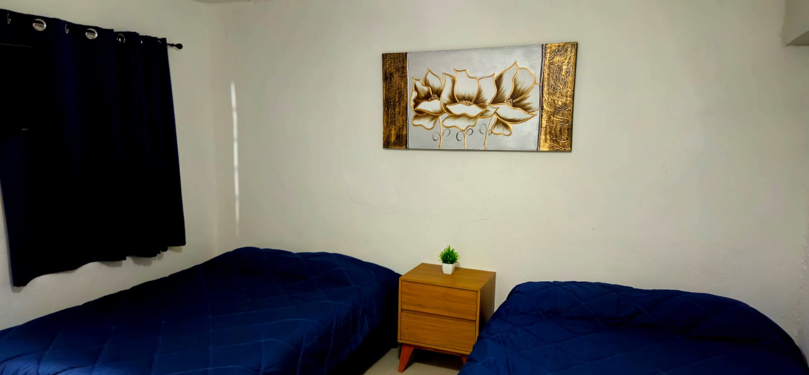 El Loft 3 donde se ve el buró, el cuadro, la cortina y las camas